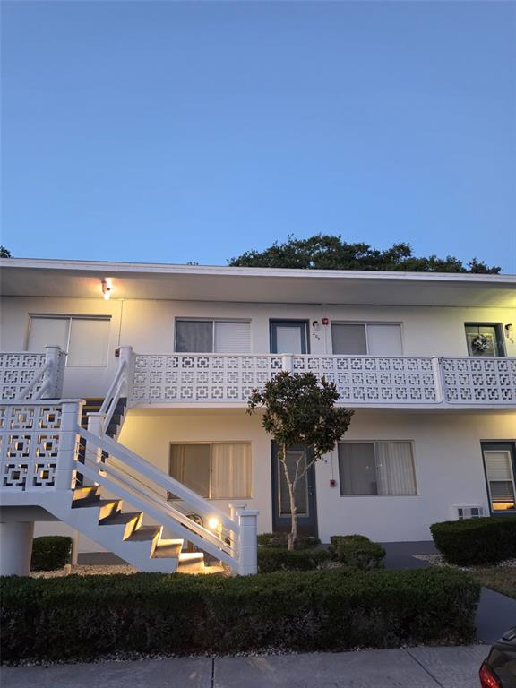 A two-story apartment building exterior features white stucco walls, a decorative balcony railing, and stairs — 8221 112TH STREET UNIT 209, SEMINOLE, FL