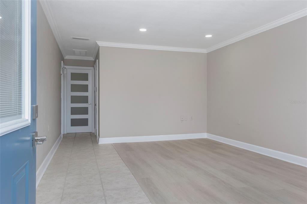 An interior view shows a room with light-colored wood flooring, tile entry, and a glass-paneled door — 8221 112TH STREET UNIT 209, SEMINOLE, FL
