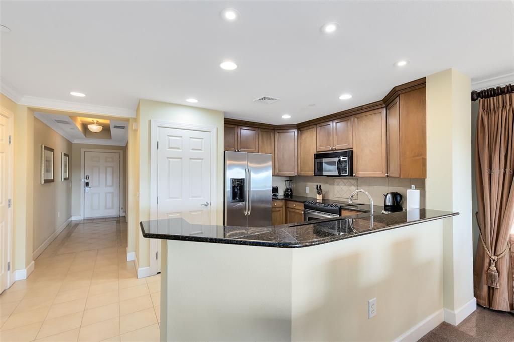 A kitchen features dark granite countertops, wood cabinets, stainless steel appliances, and tile flooring — 1360 CENTRE COURT RIDGE DRIVE UNIT 201, REUNION, FL
