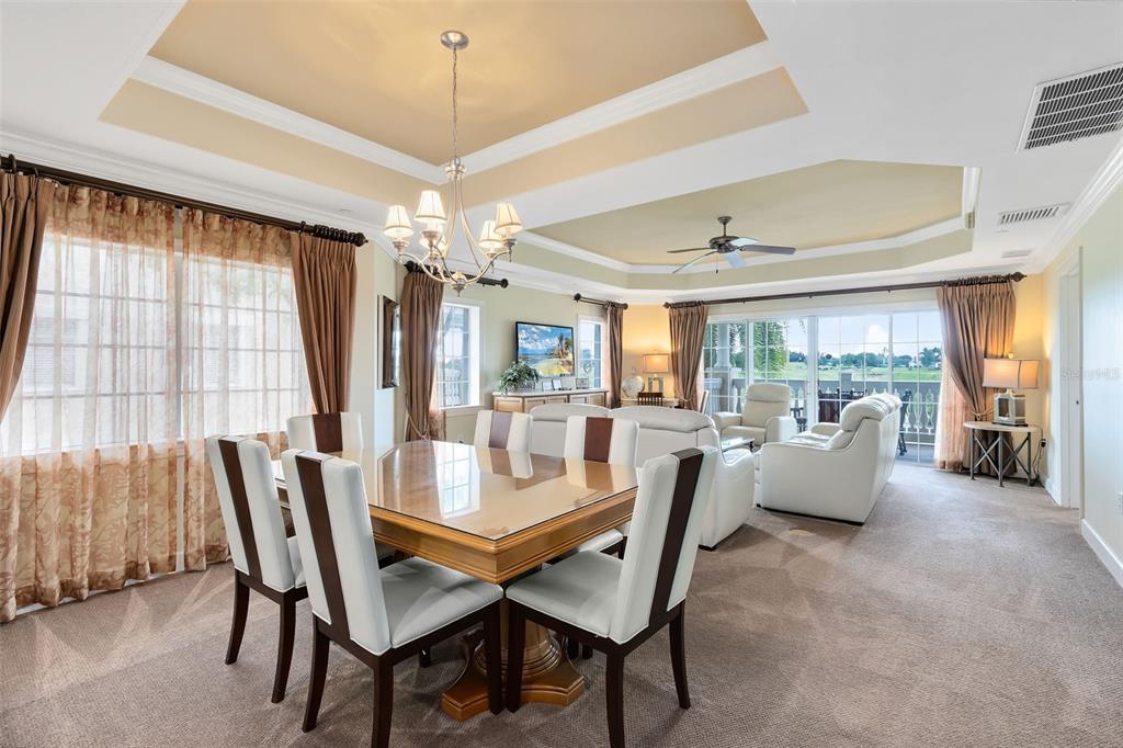 A dining area with a glass-topped table and chairs opens into a carpeted living room — 1360 CENTRE COURT RIDGE DRIVE UNIT 201, REUNION, FL