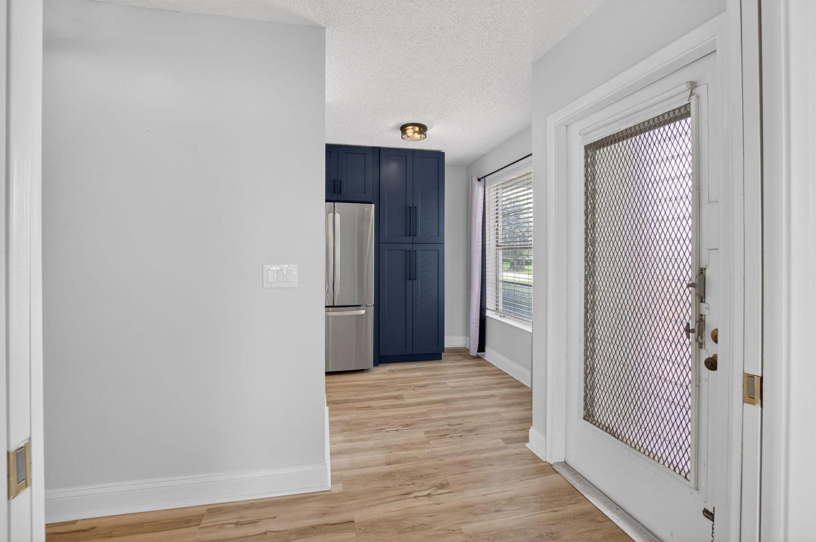 A view of a kitchen area featuring dark blue cabinetry, stainless steel appliances, and wood flooring — 2401 Del Aire Boulevard # 101, Delray Beach FL 33445, DELRAY BEACH, FL