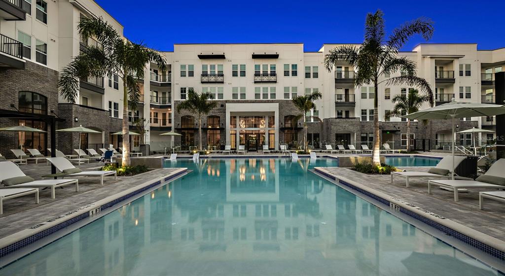 A swimming pool sits in the courtyard of a multi-story apartment building at dusk — 700 AULTMAN STREET UNIT Heritage, KISSIMMEE, FL