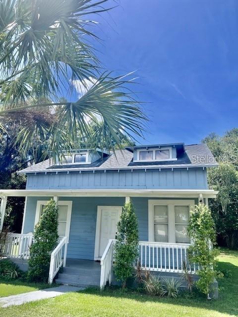 A light blue two-story house features a front porch and two dormer windows — 1635 PARTRIDGE BOULEVARD, ZEPHYRHILLS, FL