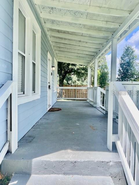 A covered wooden porch with light blue siding, white railings, and a concrete floor — 1635 PARTRIDGE BOULEVARD, ZEPHYRHILLS, FL