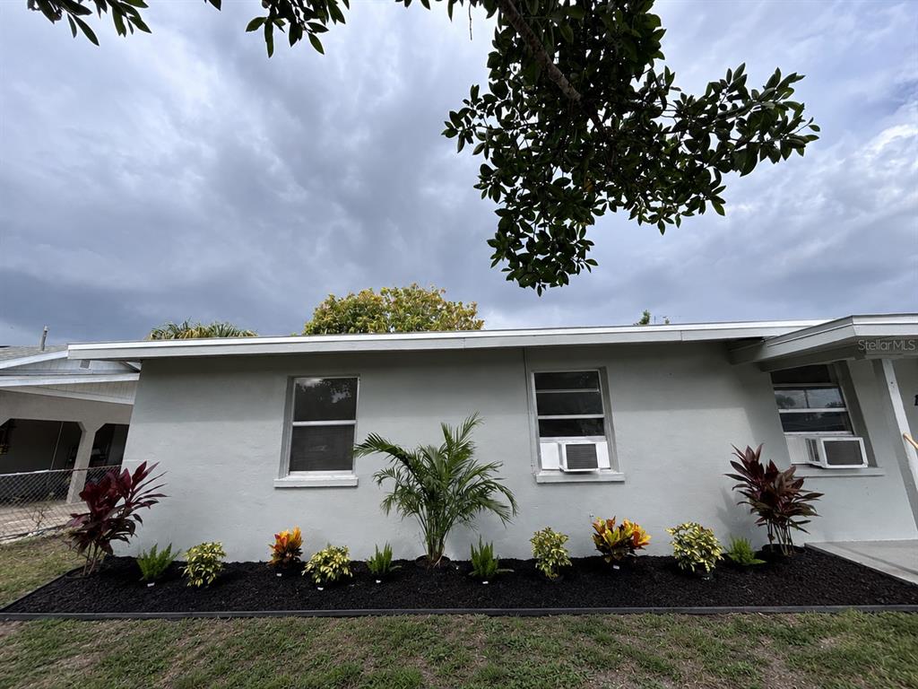 A single-story house exterior features gray stucco walls, three windows, and a landscaped garden bed — 1629 PAWNEE STREET, FORT MYERS, FL