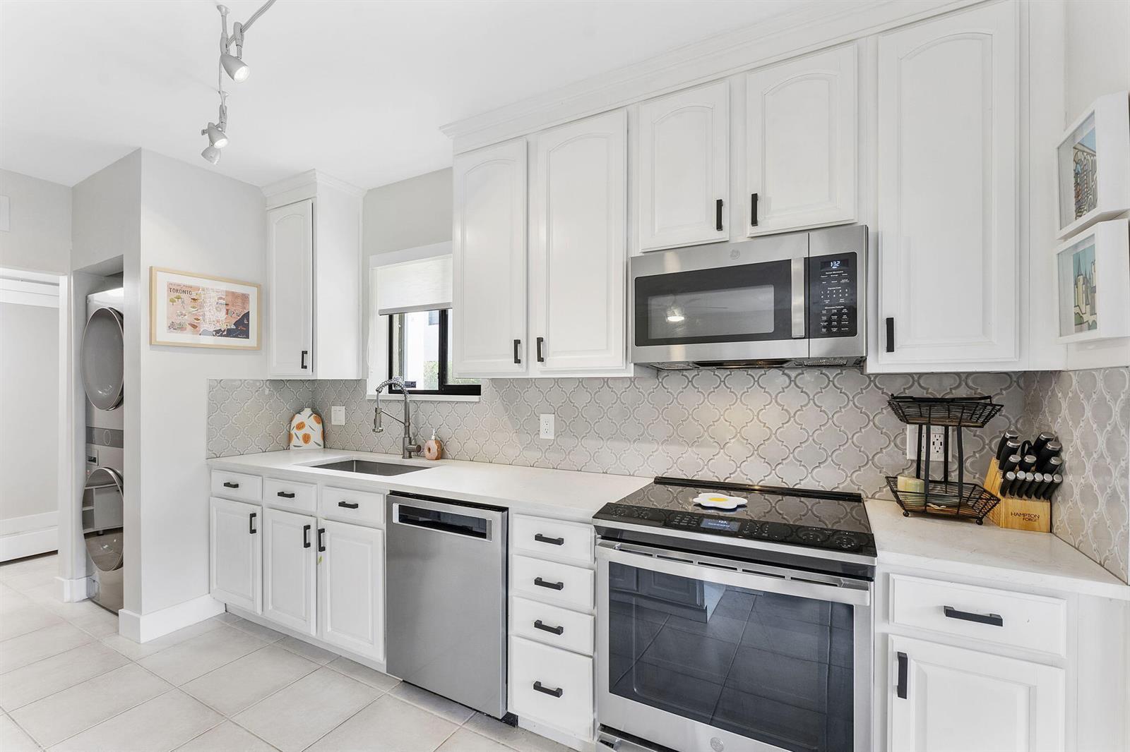 A white kitchen features quartz countertops, stainless steel appliances, and a sliding glass door — 6314 Longboat Lane W, Boca Raton FL 33433, BOCA RATON, FL