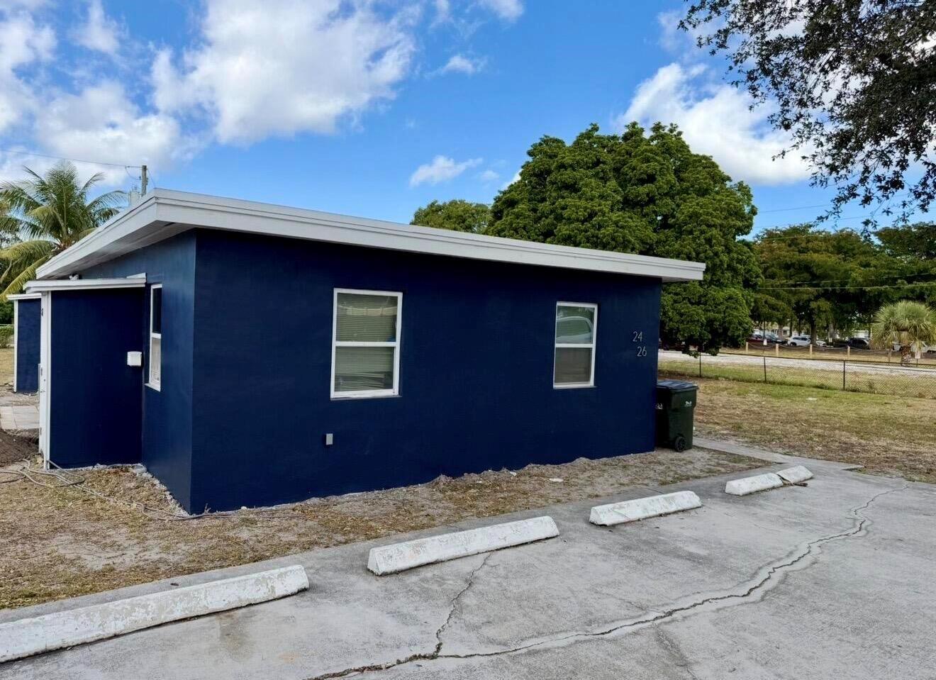A dark blue exterior wall of a single-story building with two windows and parking spaces — 24 SW 10th Avenue, Delray Beach FL 33444, DELRAY BEACH, FL