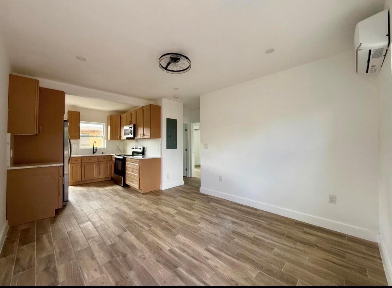 An open-concept kitchen and living area with light wood-look tile flooring and white walls — 24 SW 10th Avenue, Delray Beach FL 33444, DELRAY BEACH, FL