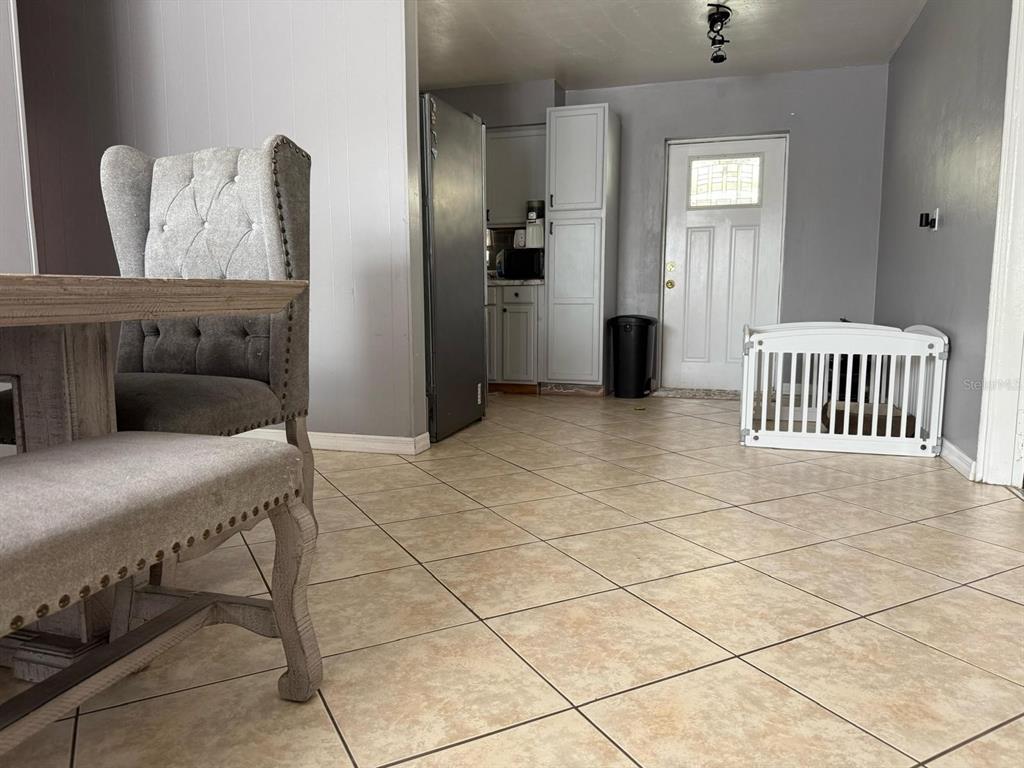 A dining area with tile flooring leads into a kitchen with light gray cabinetry — 311 CONGRESS AVENUE, AUBURNDALE, FL
