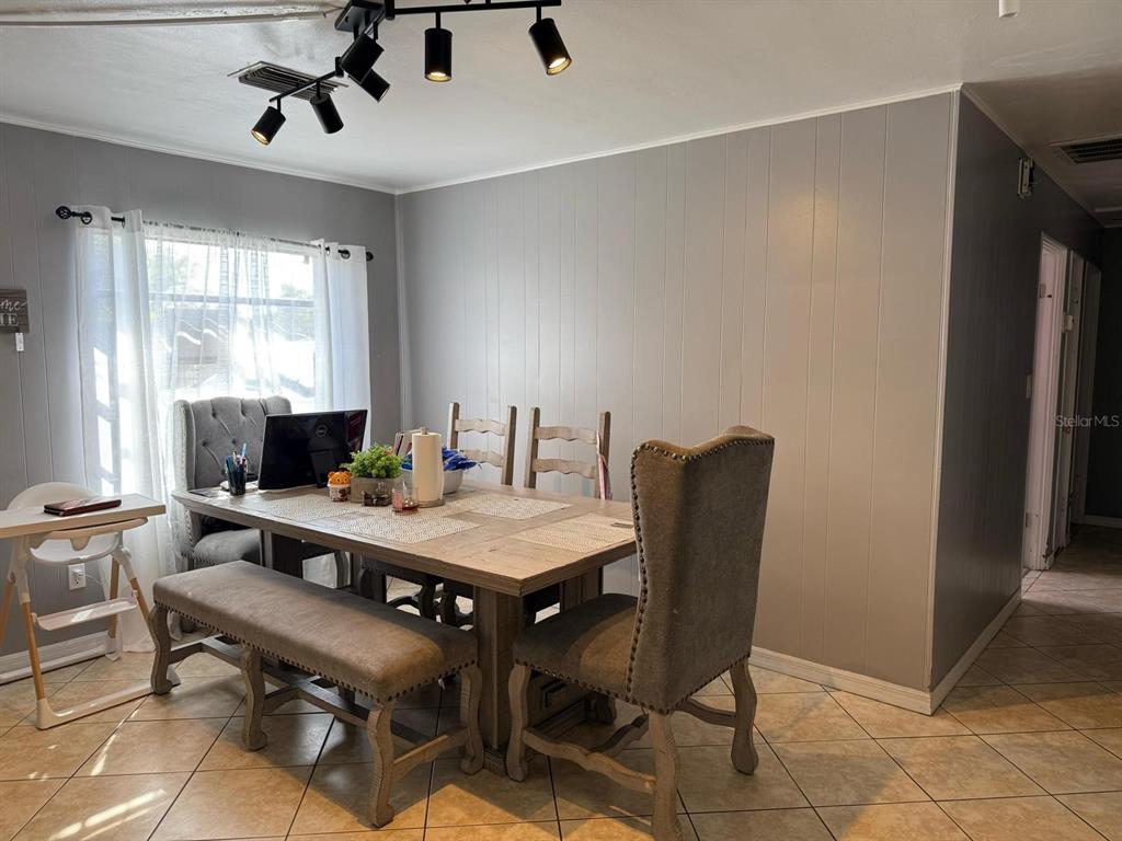 A dining room features a wooden table, upholstered chairs, a bench, and track lighting — 311 CONGRESS AVENUE, AUBURNDALE, FL