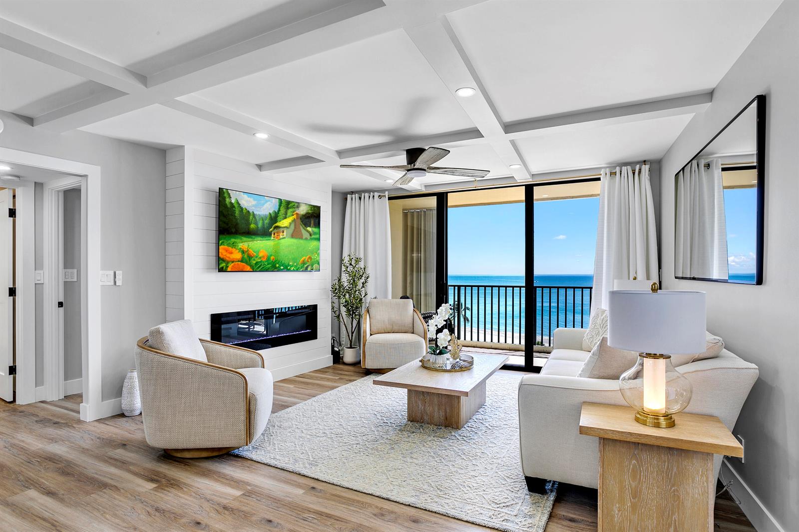A living room features a fireplace, wall-mounted television, coffered ceiling, and a balcony with ocean views — 300 Ocean Trail Way # 908, Jupiter FL 33477, JUPITER, FL
