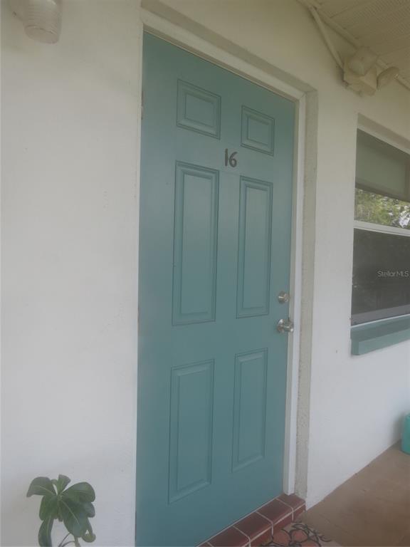A teal-colored front door marked with the number 16 on a white exterior wall — 5815 18TH STREET N UNIT 16, ST PETERSBURG, FL