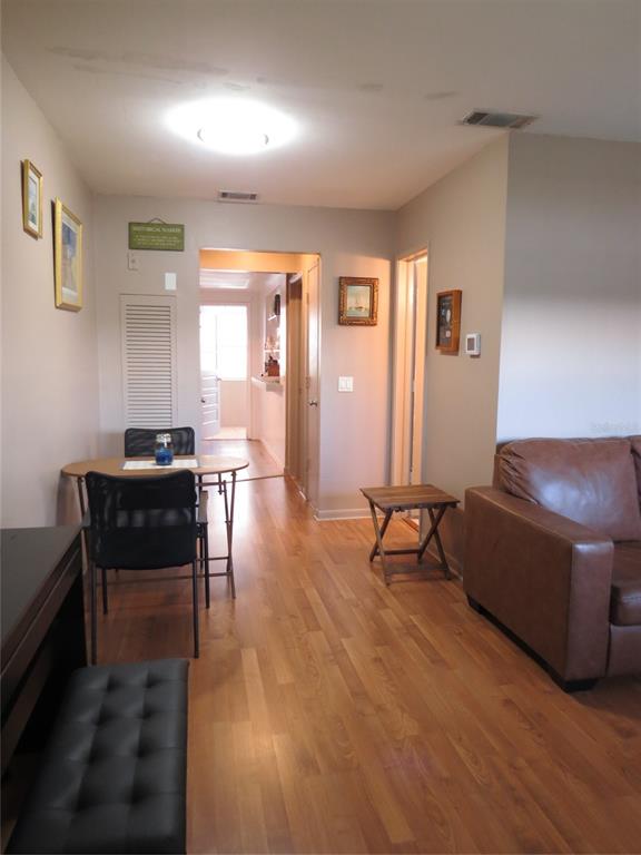 A living and dining area features wood flooring, a brown leather sofa, and a small table — 5815 18TH STREET N UNIT 16, ST PETERSBURG, FL
