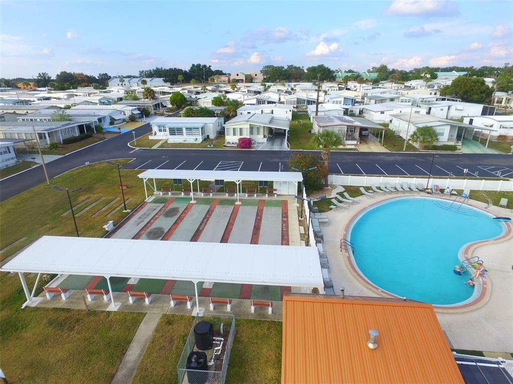 An aerial view shows a community pool and shuffleboard courts next to a residential neighborhood — 37832 MADEIRA AVENUE, ZEPHYRHILLS, FL