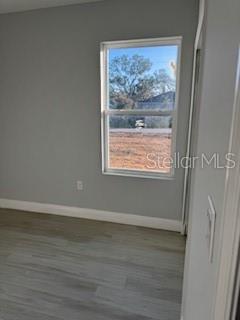 A hallway with light wood-look flooring leads to a doorway and a bedroom with a window — 17174 NIXON AVENUE, PORT CHARLOTTE, FL