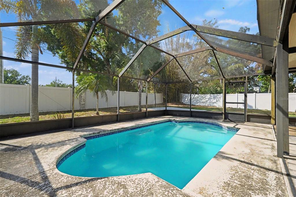 A screened-in swimming pool sits on a concrete patio in a fenced backyard — 1714 LARABIE COURT, BRANDON, FL