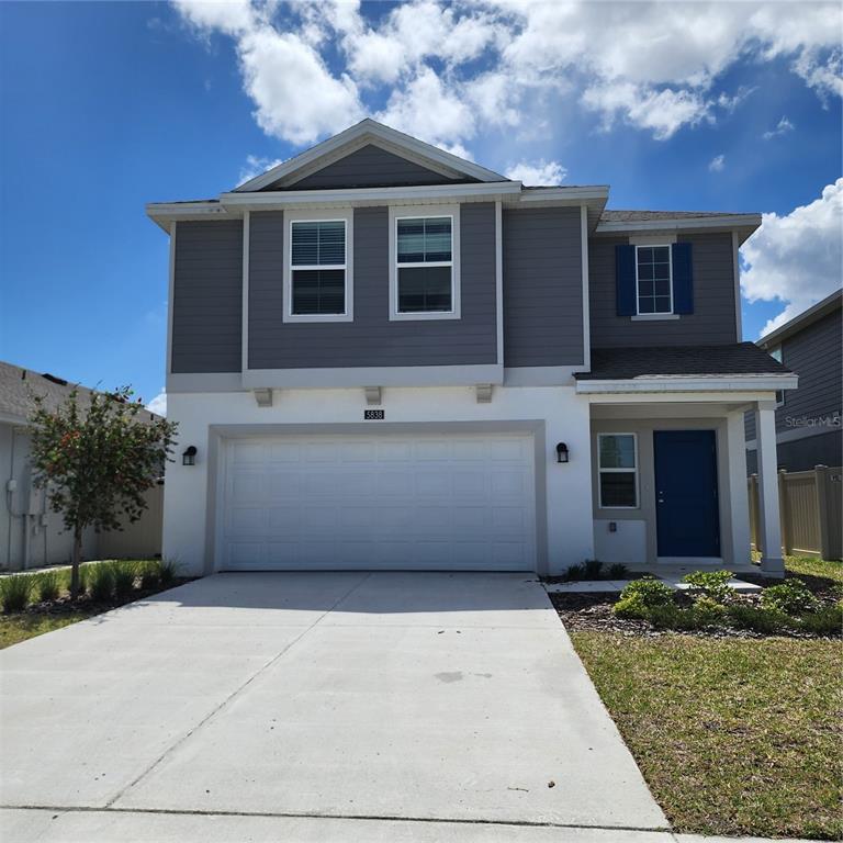 A two-story house features a white stucco lower level, gray siding above, and a garage — 5838 LE MARIN WAY, KISSIMMEE, FL