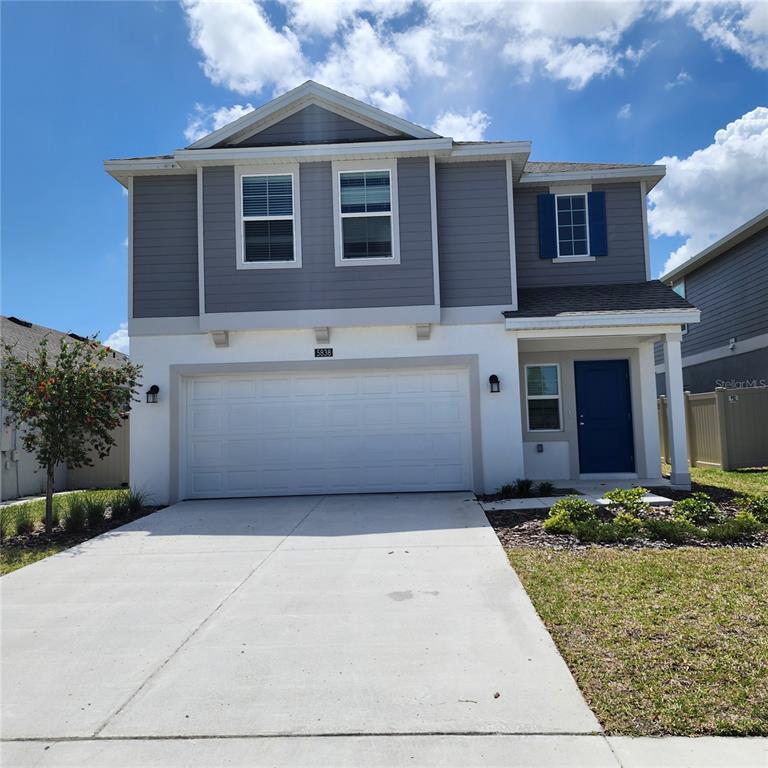 A two-story house with a white stucco lower level, gray siding, and a two-car garage — 5838 LE MARIN WAY, KISSIMMEE, FL