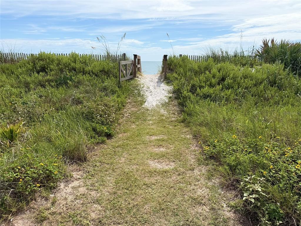 A grassy path leads through a wooden gate toward a sandy beach and the ocean — 00 S OCEAN SHORE BOULEVARD, FLAGLER BEACH, FL