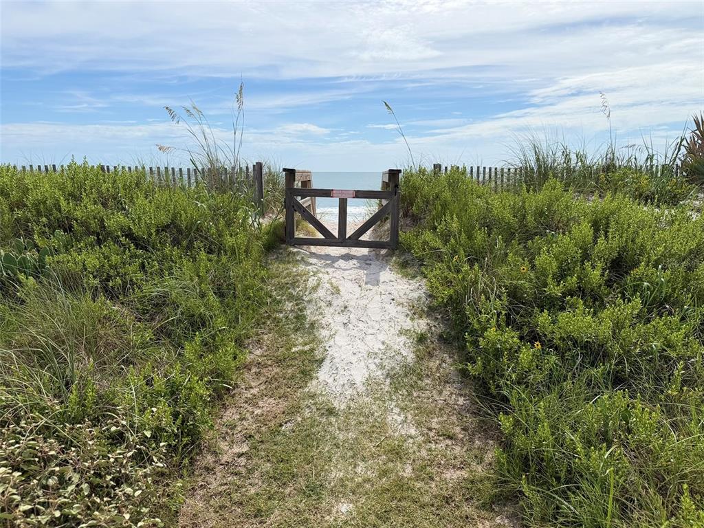 A sandy path leads through coastal vegetation to a wooden gate overlooking the ocean — 00 S OCEAN SHORE BOULEVARD, FLAGLER BEACH, FL