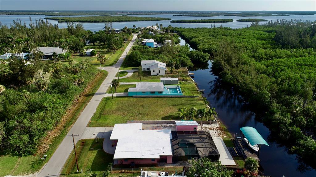An aerial view shows houses along a canal leading to a large body of water — 232 DARST AVENUE, PUNTA GORDA, FL