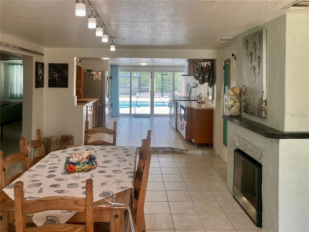 A dining area with a wooden table leads into a kitchen and a pool view — 232 DARST AVENUE, PUNTA GORDA, FL