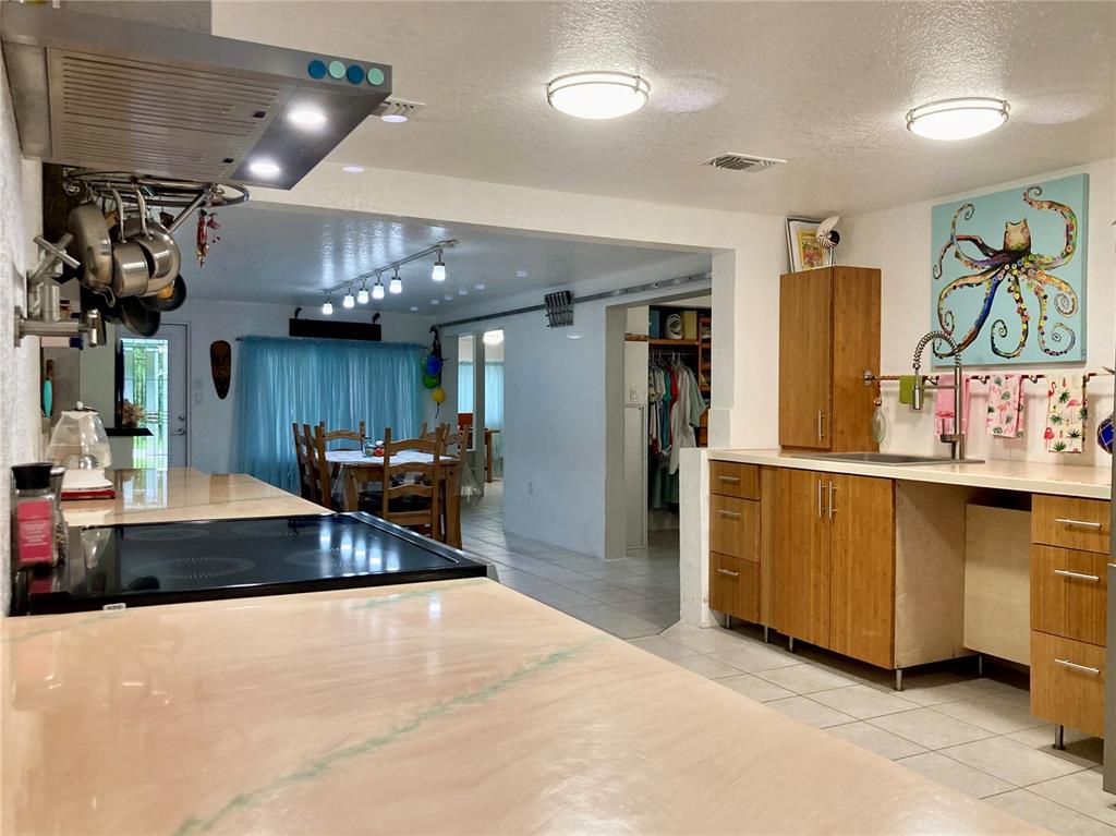 A kitchen with light-colored countertops and wood cabinets overlooks a dining area — 232 DARST AVENUE, PUNTA GORDA, FL