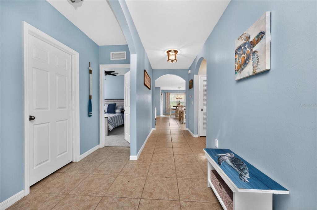 A hallway with light blue walls, tile flooring, and a bench featuring turtle artwork — 7164 MIKASA DRIVE, PUNTA GORDA, FL