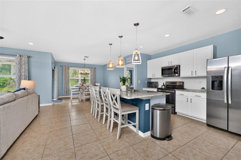 A kitchen with white cabinets, granite countertops, and a breakfast bar with four chairs — 7164 MIKASA DRIVE, PUNTA GORDA, FL