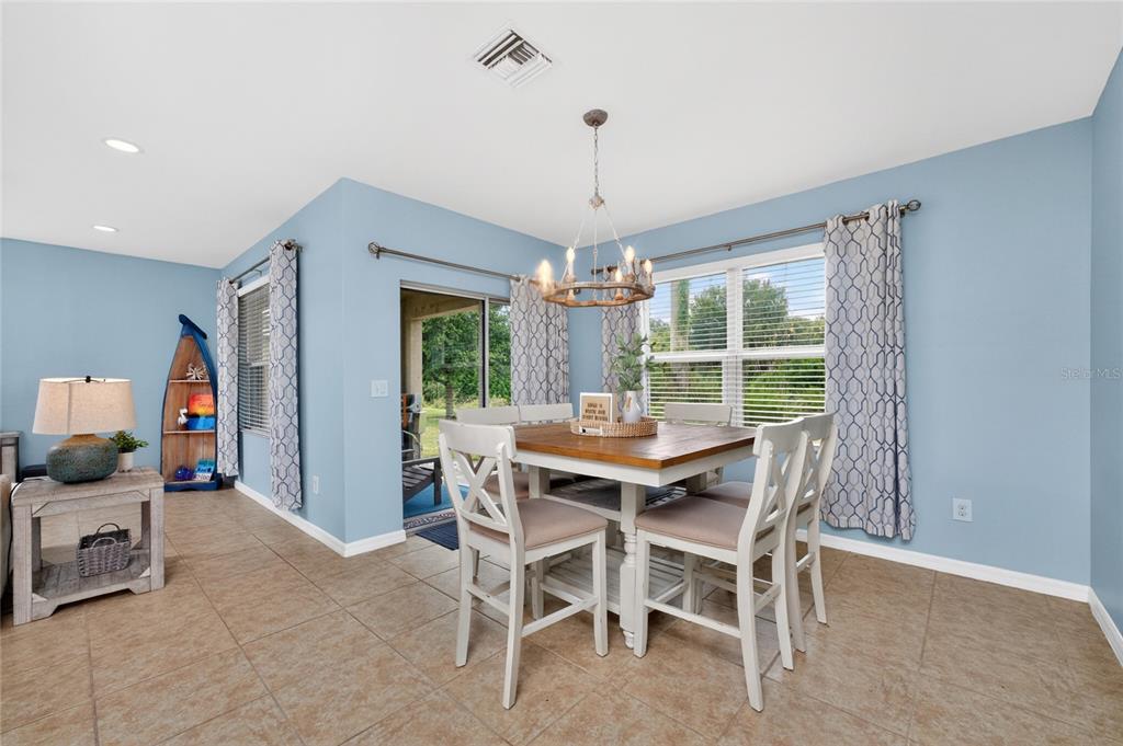 A dining area features light blue walls, tile flooring, a wooden table, and a chandelier — 7164 MIKASA DRIVE, PUNTA GORDA, FL