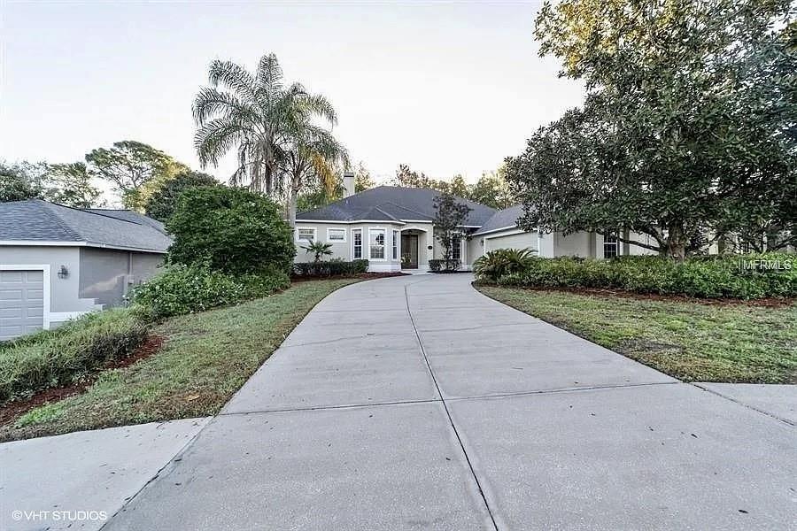 A concrete driveway leads to the front entrance of a single-story suburban house — 13200 WHISPER BAY DRIVE, CLERMONT, FL