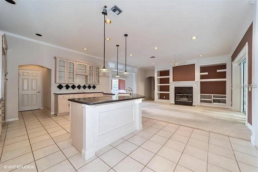 A kitchen with a center island and tile flooring opens into a carpeted living area — 13200 WHISPER BAY DRIVE, CLERMONT, FL