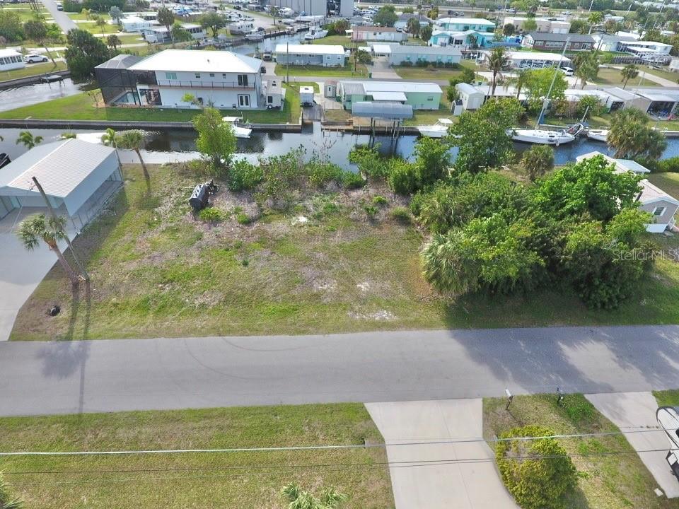 An aerial view shows a vacant waterfront lot with vegetation and a concrete driveway — 4287 NETTLE ROAD, PORT CHARLOTTE, FL