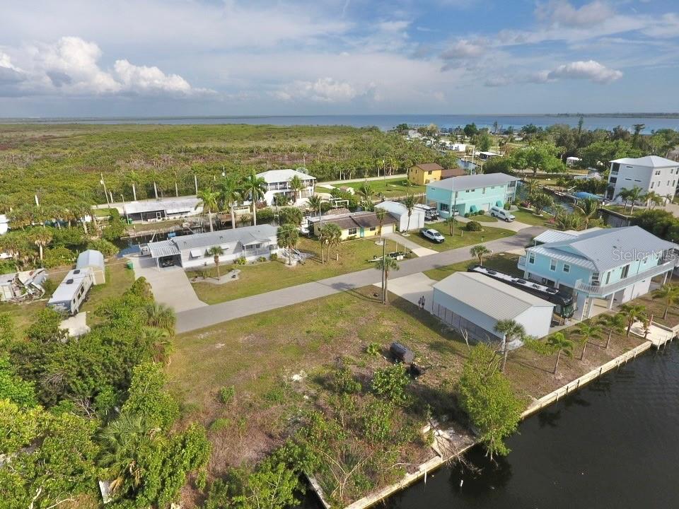 An aerial view shows several houses, a canal, and surrounding vegetation in a coastal area — 4287 NETTLE ROAD, PORT CHARLOTTE, FL