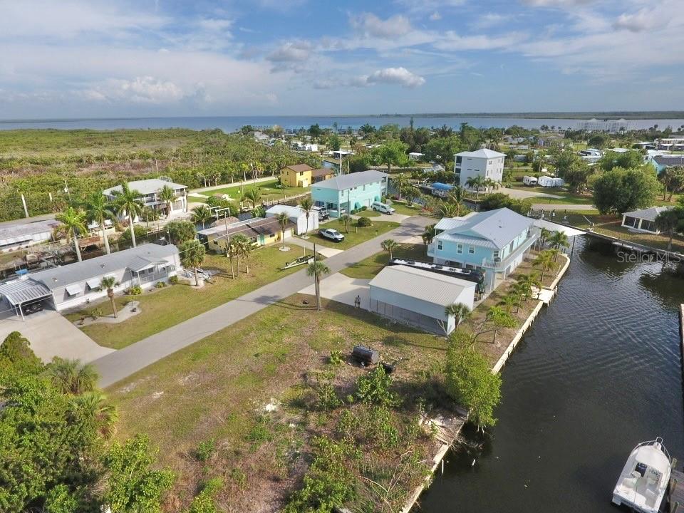 An aerial view shows several houses along a canal leading to a large body of water — 4287 NETTLE ROAD, PORT CHARLOTTE, FL