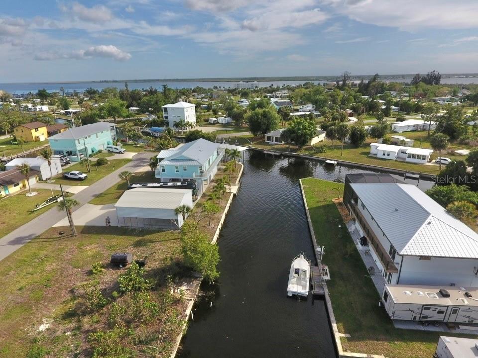 An aerial view shows a canal flowing between residential properties with houses and parked vehicles — 4287 NETTLE ROAD, PORT CHARLOTTE, FL