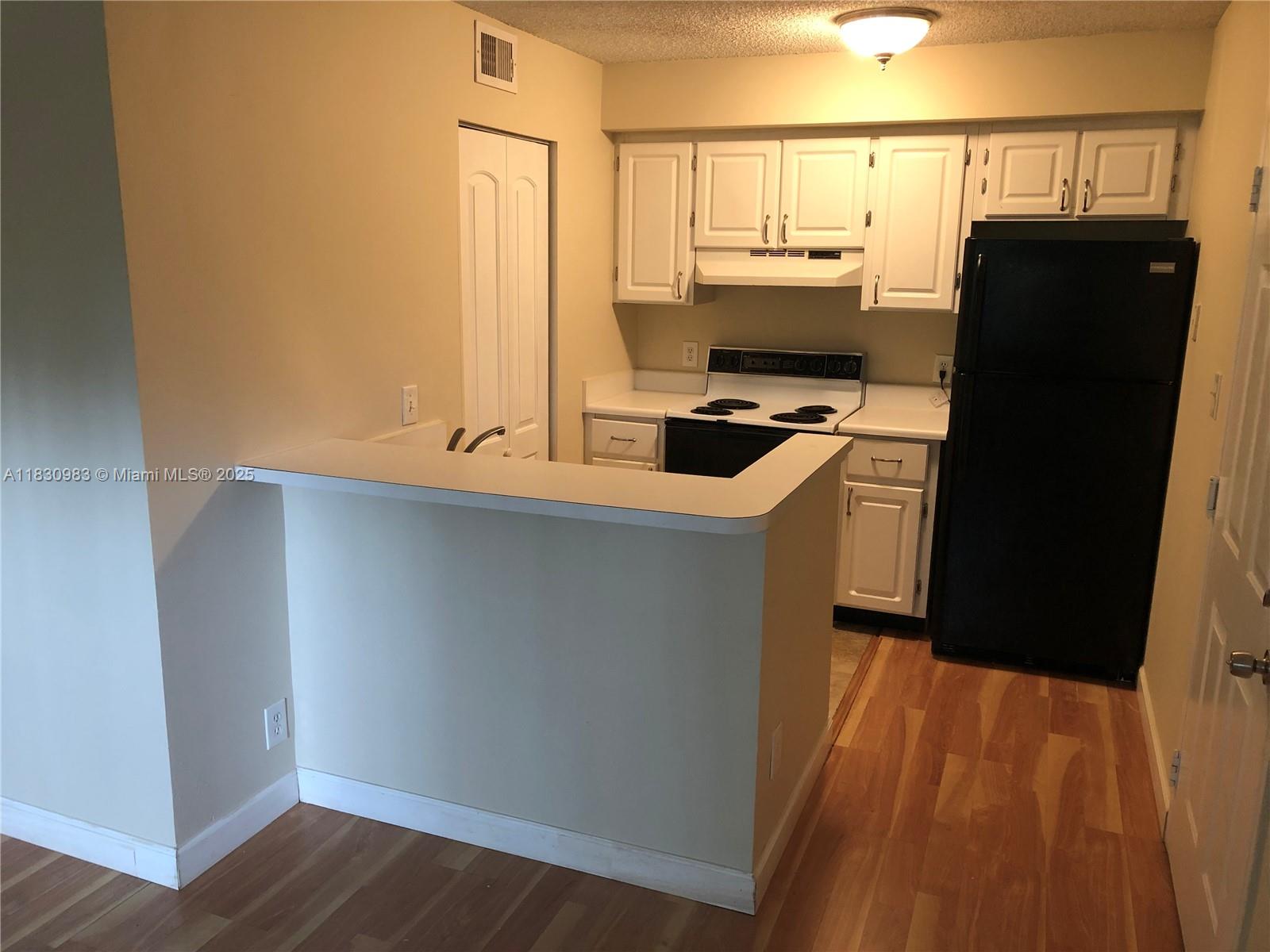 A kitchen features white cabinets, a black refrigerator, a stove, and a breakfast bar — 620 S Park Rd # 2, Hollywood FL 33021, HOLLYWOOD, FL