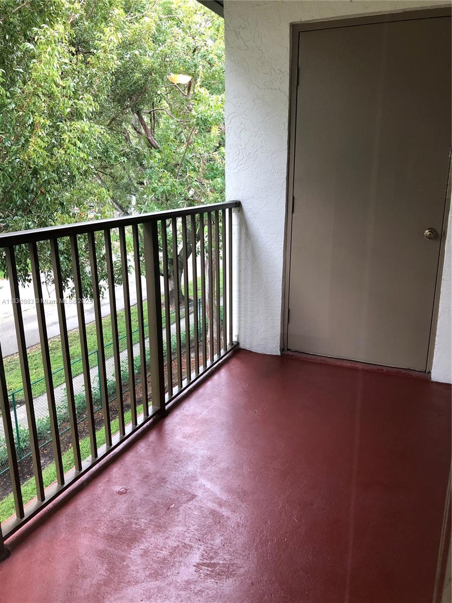 A balcony with a red floor, metal railing, and a closed door leading inside — 620 S Park Rd # 2, Hollywood FL 33021, HOLLYWOOD, FL