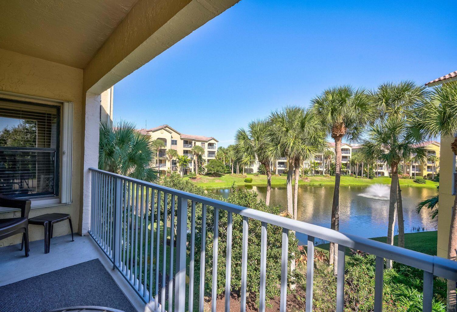 A balcony with a metal railing overlooks a pond, palm trees, and apartment buildings — 300 Uno Lago Drive # 305, Juno Beach FL 33408, JUNO BEACH, FL