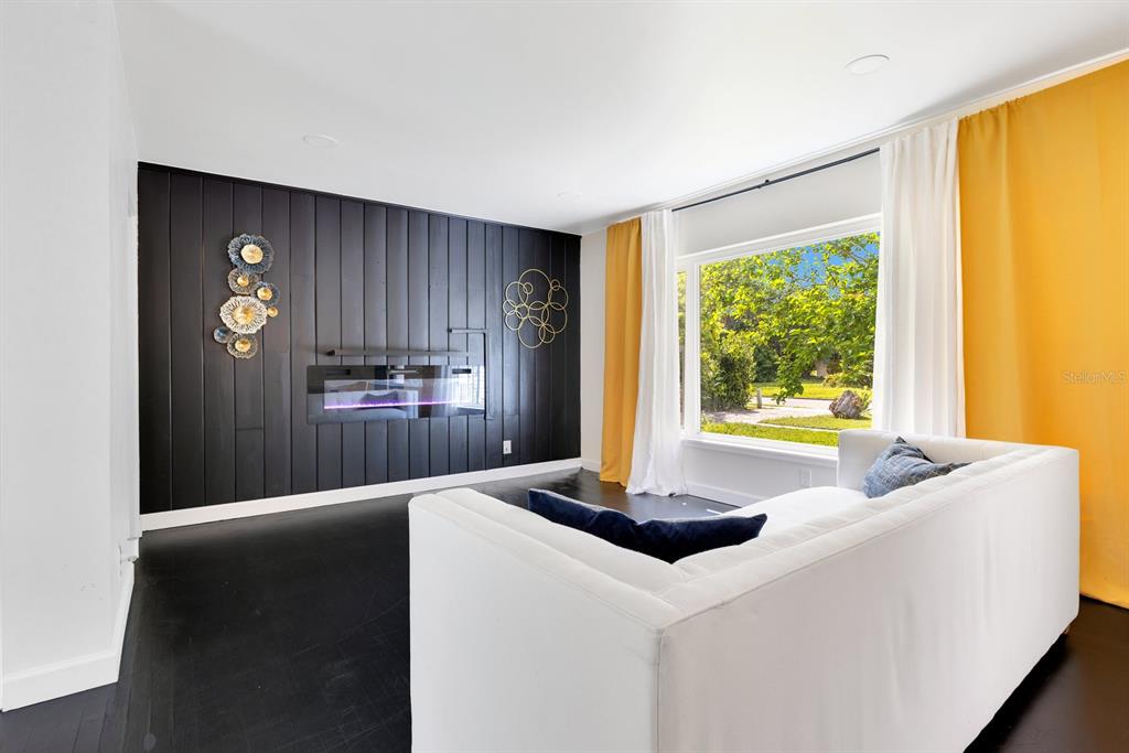 A living room features a black wood-paneled accent wall with a fireplace and yellow curtains — 344 STARLING ROAD, WINTER PARK, FL