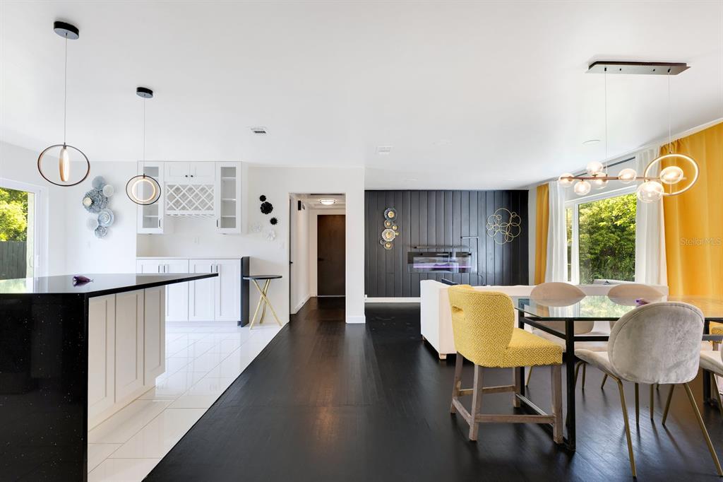 A modern open-concept kitchen and dining area features white cabinetry, black flooring, and yellow accents — 344 STARLING ROAD, WINTER PARK, FL