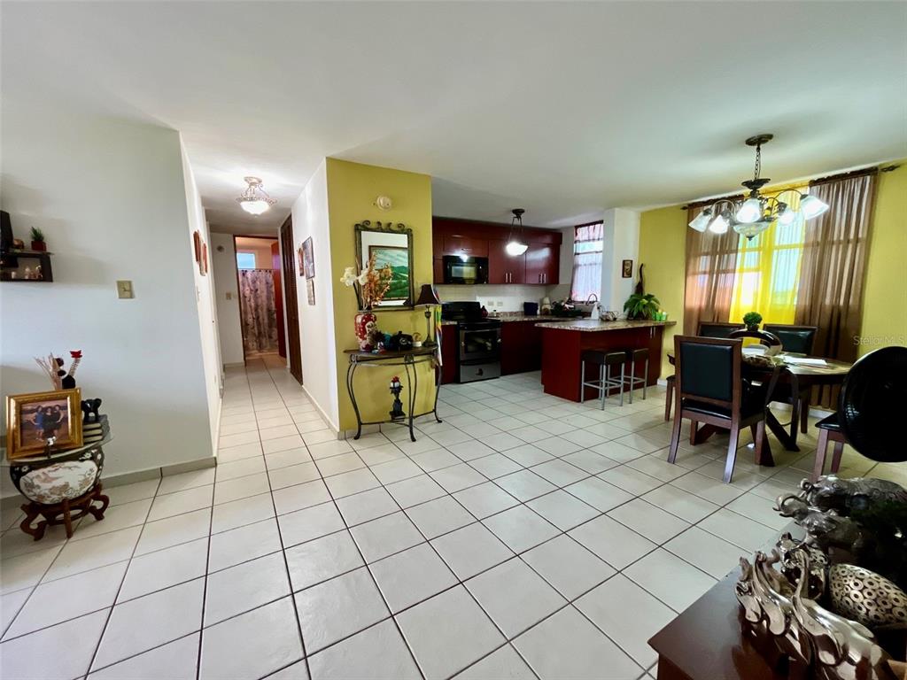 An open-concept kitchen and dining area features tile flooring, dark wood cabinets, and yellow walls — Cond. La Loma B-104 UNIT 104, FAJARDO, PR