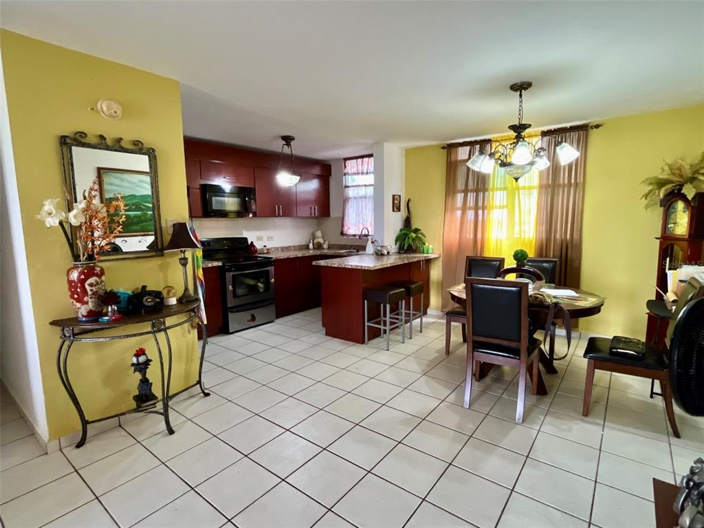 A kitchen with dark wood cabinets and a dining area with a chandelier and table — Cond. La Loma B-104 UNIT 104, FAJARDO, PR