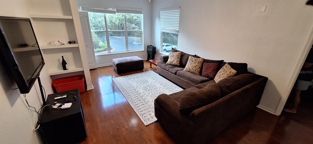 A living room features a brown sectional sofa, a patterned area rug, and built-in shelving — 8927 LEGACY COURT UNIT 201, KISSIMMEE, FL