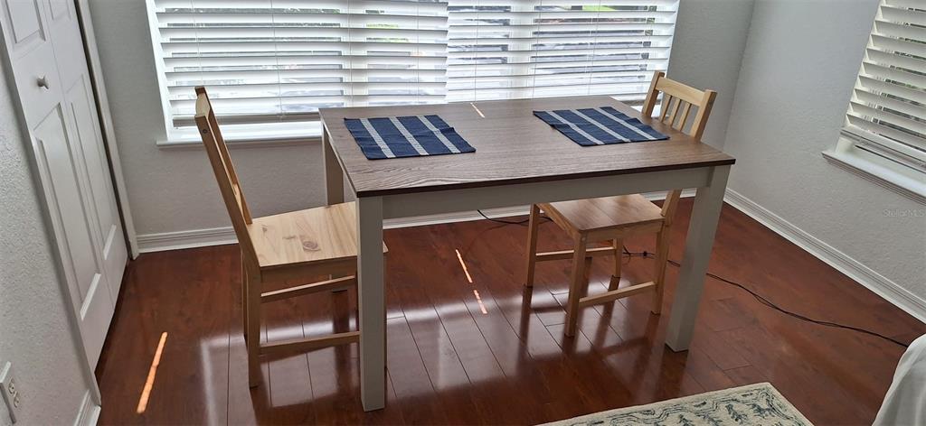 A dining area features a wooden table with two chairs on a hardwood floor — 8927 LEGACY COURT UNIT 201, KISSIMMEE, FL