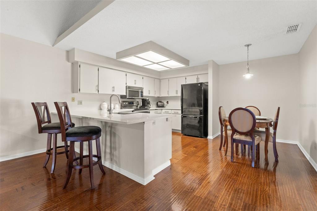 A kitchen with white cabinets, a breakfast bar, and a dining area with hardwood floors — 23315 CLUB VILLAS DRIVE, LAND O LAKES, FL