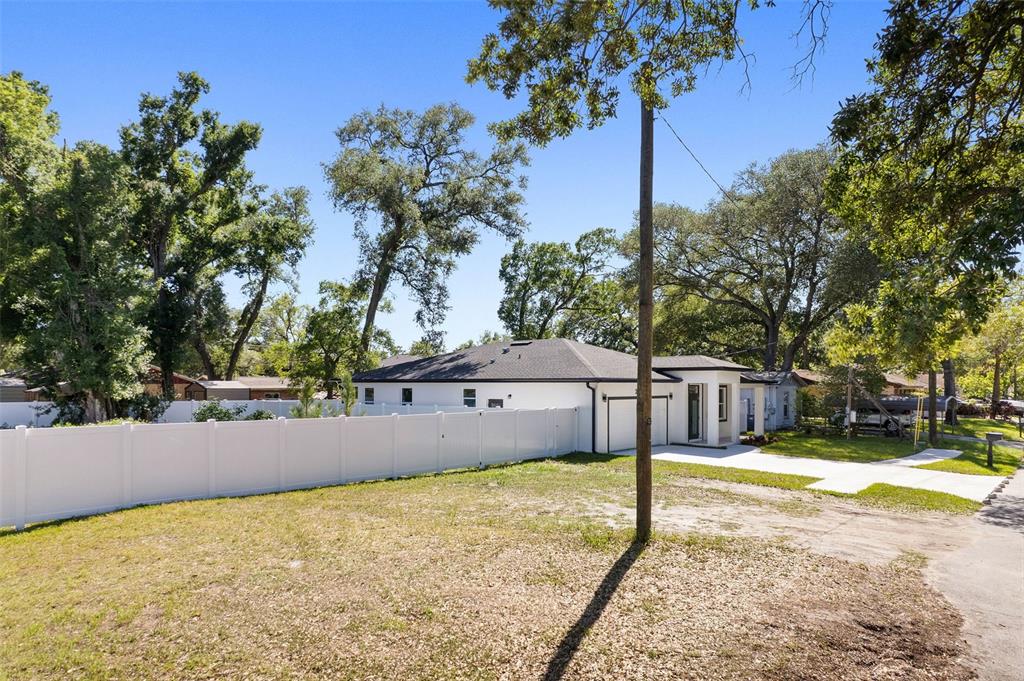 A white house with a dark roof sits behind a white vinyl privacy fence — 2619 E PALIFOX STREET, TAMPA, FL