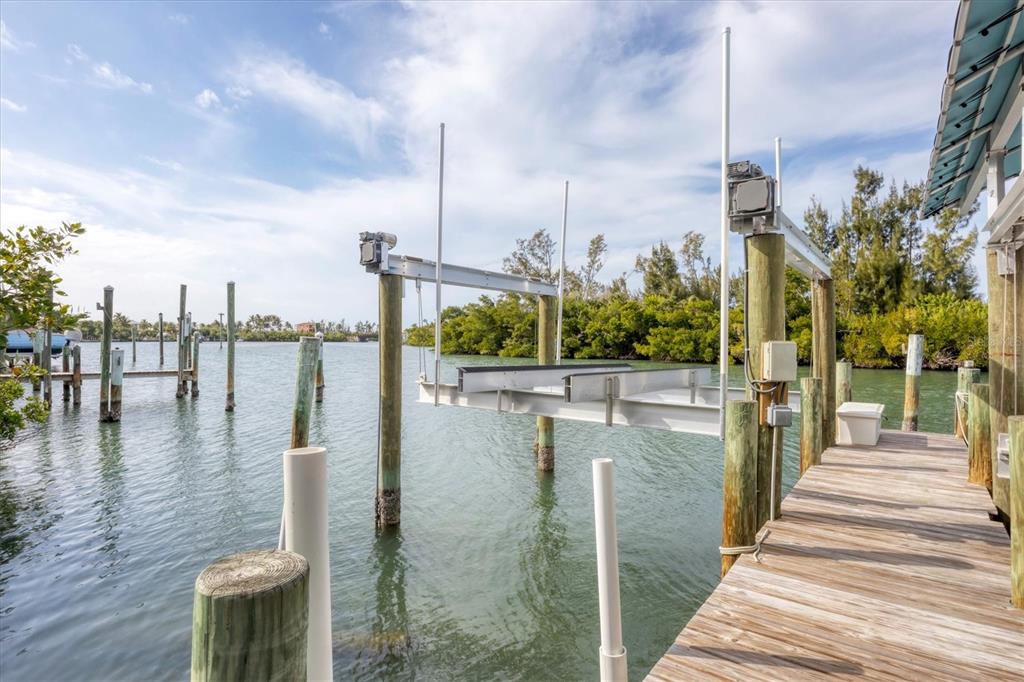 A wooden dock features a boat lift extending over the water toward a mangrove shoreline — 6 POINTE WAY, PLACIDA, FL