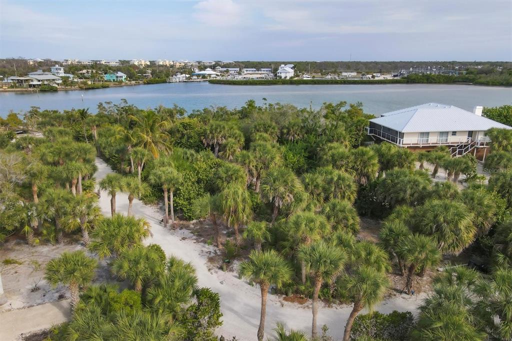 An aerial view shows a sandy path winding through palm trees toward a waterfront house — 6 POINTE WAY, PLACIDA, FL