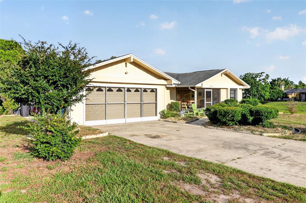 A single-story house with a two-car garage and a front yard under a blue sky — 7465 GALLOWAY ROAD, WEEKI WACHEE, FL
